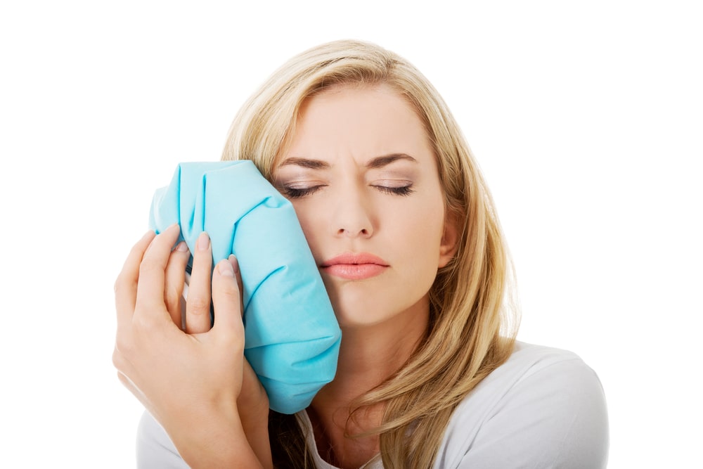 woman using an ice pack on her cheek